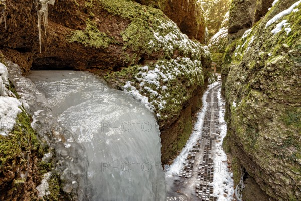Frozen waterfall in a narrow gorge, lined with mossy rocks and snow, The Dragon Gorge near Eisenach in Thuringia