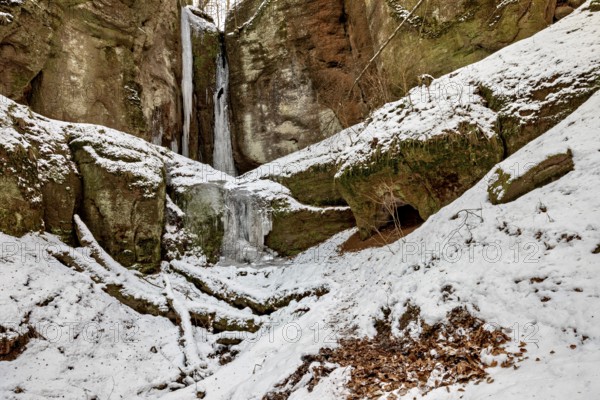 Snow-covered rocky landscape with icicles and a small cave, the Dragon Gorge near Eisenach in Thuringia