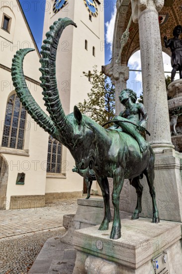 Bronze sculpture of a horseman next to a church with a tower and artistic arches in the background, The fountain in the town of Kempten im Allgäu
