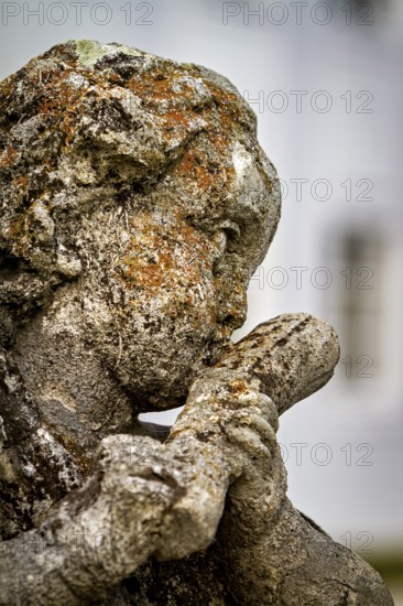 Close-up of a weathered stone sculpture of a head covered in moss, stone statues in the town of Kempten im Allgäu