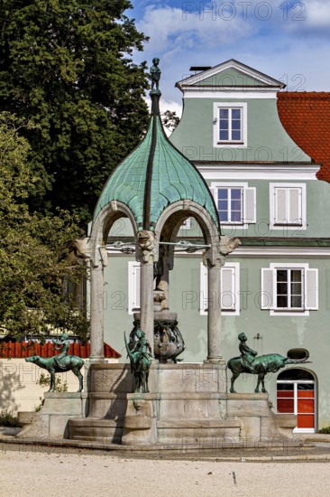 Historic fountain with green dome in front of a building with white windows in summer, The fountain in the town of Kempten im Allgäu