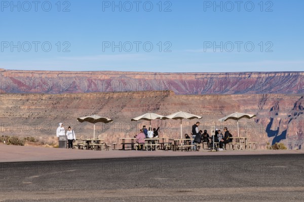 Tourists waiting for bus transportation at covered picnic tables at Guano Point in Grand Canyon West near Peach Springs, Arizona