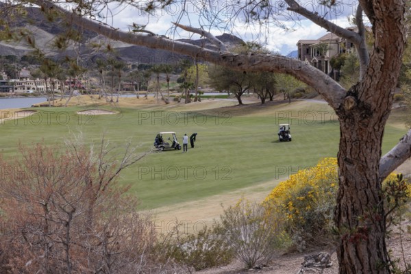 Golfers playing on a golf course along the shoreline of Las Vegas Wash at Lake Las Vegas in Henderson, Nevada, USA