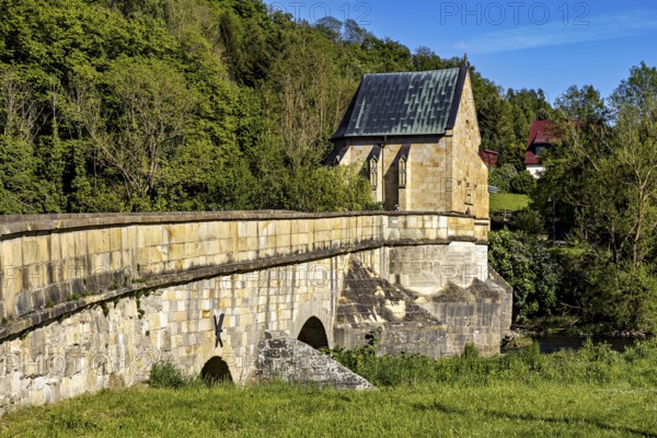 Side view of a historic stone bridge with a chapel and lush vegetation in the background, The historic Werra Bridge at Creuzburg in Thuringia