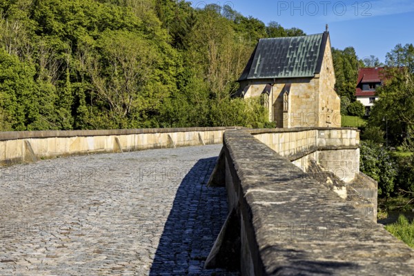 Close-up of a cobblestone road on a stone bridge leading to a chapel, surrounded by forest, The historic Werra bridge of Creuzburg in Thuringia