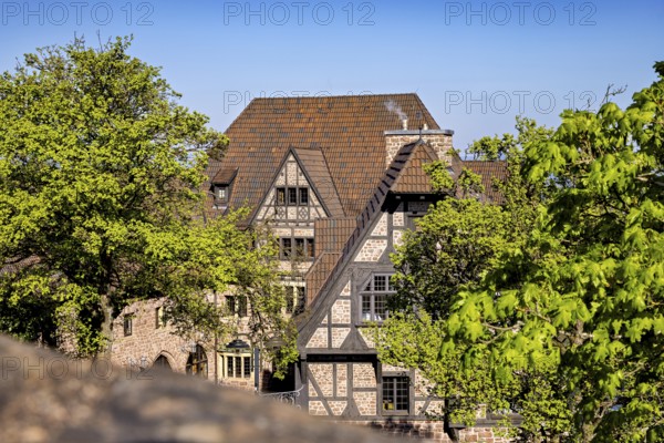 Half-timbered house surrounded by trees on a sunny day with a blue sky, The Hotel zur Wartburg near Eisenach in Thuringia