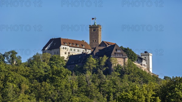 Castle with striking tower rises above green forests, Wartburg Castle near Eisenach in Thuringia