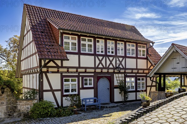 A traditional half-timbered house with red roof tiles and bench in a sunny rural courtyard, Historic half-timbered houses in the town of Treffurt in Thuringia