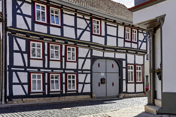 A traditional half-timbered house with a characteristic wooden structure and small windows in a cobbled alley, Historic half-timbered houses in the town of Treffurt in Thuringia
