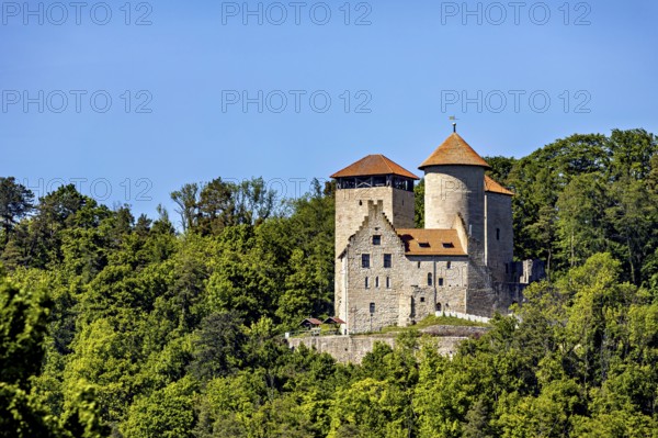 Medieval castle with towers, surrounded by dense forest in bright sunshine, Normannstein Castle near Treffurt in Thuringia