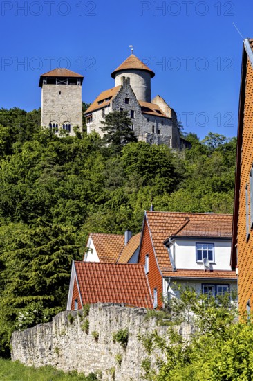 Half-timbered houses with red roofs in front of a castle on a wooded hill, Normannstein Castle near Treffurt in Thuringia
