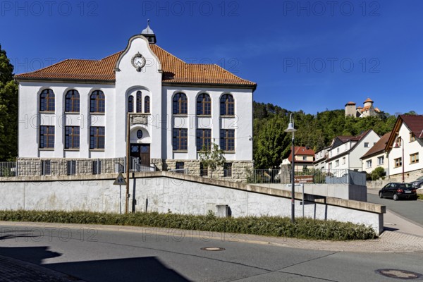 A white building with red tiled roofs in a small, quiet village under a blue sky, the town of Treffurt in Thuringia