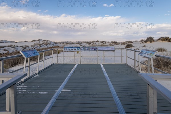 Signage informs visitors about dunes and wildlife along the Interdune Boardwalk over the gypsum sand dunes in White Sands National Park near Alamogordo, New Mexico