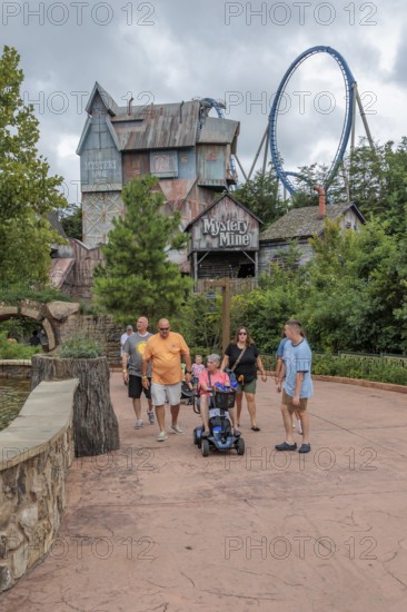 Family of park guests walking past the Mystery Mine roller coaster ride at the Dollywood amusement park in Pigeon Forge, TN