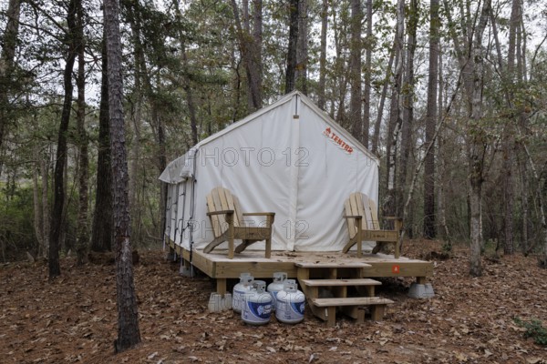 Propane tanks outside a Tentrr glamping tent on a raised platform with a wooden porch at Clarko State Park near Quitman, Mississippi, USA