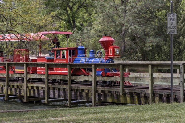 Hermann Park Railroad train, a one-third size replica of an 1863 C.P. Huntington steam train crosses a bridge over a part of McGovern Lake in Hermann Park in downtown Houston, Texas