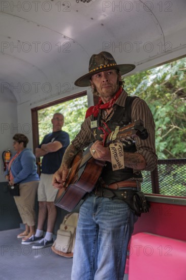 Singer and entertainer travels from car to car singing songs to the passengers for tips on the Great Smoky Mountains Railroad excursion from Bryson City, North Carolina