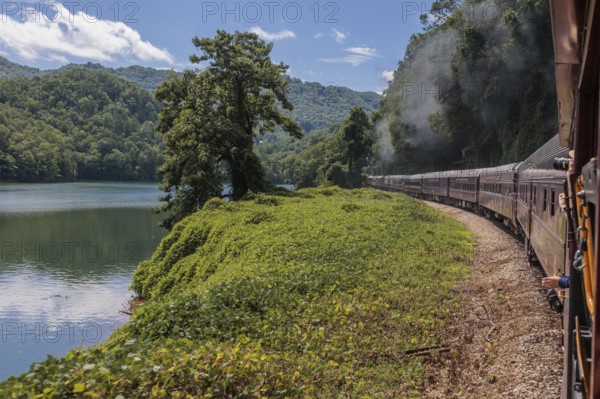 Steam from the Great Smoky Mountains Railroad hangs in the air as the train rounds a curve through the mountains of North Carolina