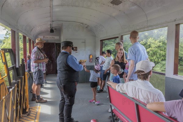 Young family watches a ticket collector punch their souvenir tickets on the Great Smoky Mountains Railroad excursion from Bryson City, North Carolina