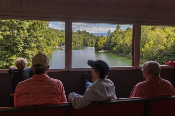 Great Smoky Mountains Railroad passengers looking out the windows of the open air train car while on an excursion from Bryson City, North Carolina