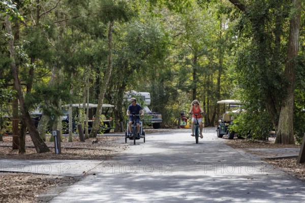 Man and woman ride bicycles through a camping loop at Fort Wilderness campground at Walt Disney World in Orlando, Florida, USA