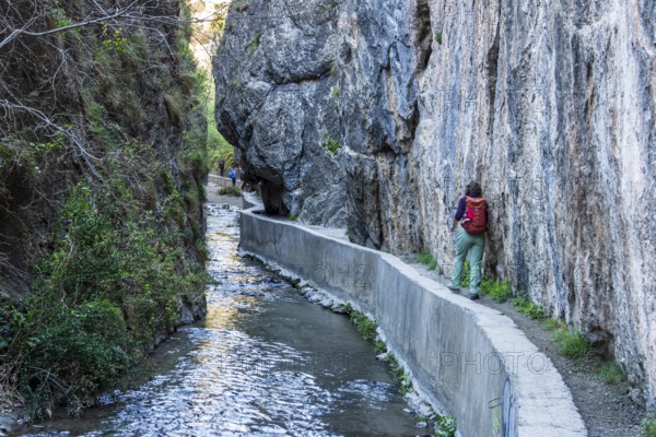 Woman on narrow hiking path Los Cahorros de Monachil, along the Rio Monachil river, narrow path in the river gorge, Monachil near Granada, Andalusia, Spain