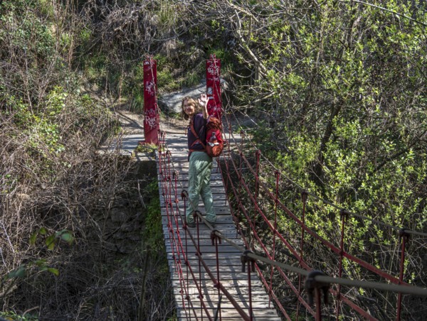 Woman on suspension bridge, hiking path Los Cahorros de Monachil, along the Rio Monachil river, narrow path in the river gorge, Monachil near Granada, Andalusia, Spain