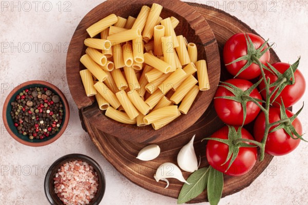 Pasta ingredients spread out, on a wooden surface, with tomatoes and spices, ready to cook, there are no people