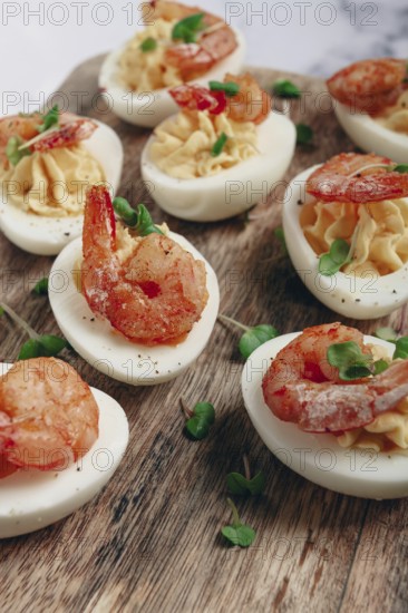Boiled eggs stuffed with yolk and seasoned with mayonnaise, stuffed eggs with shrimp, on a wooden chopping board, selective focus, close-up, no people