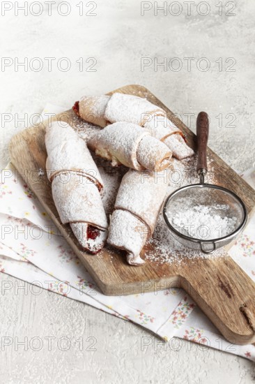 Bagels with filling, sweet pastries, sprinkled with powdered sugar, on a wooden board, dessert, breakfast