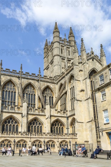 People relaxing on benches Bath Abbey church yard, city of Bath, north east Somerset, England, UK