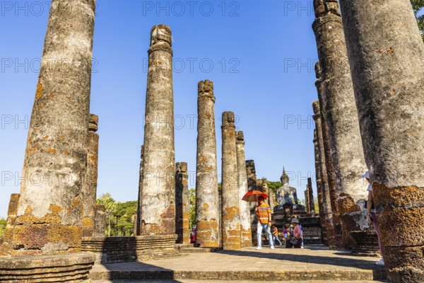 Visitors between columns in the historic Buddhist temple complex Wat Mahathat, historical park, Sukhothai, Sukhothai province, Thailand