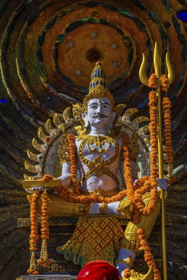 Hindu deity Shiva holding a trident, offerings in the foreground, a cosmic symbol in the back, Buddhist temple complex Wat Phra That Sorn Kaew, Phetchabun province, Thailand