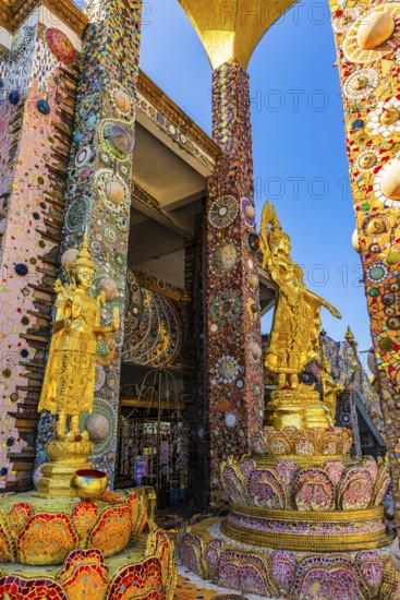 Gilded Buddha statues standing on pedestals decorated with mosaics and glass works of art, Buddhist temple complex Wat Phra That Sorn Kaew, Phetchabun province, Thailand