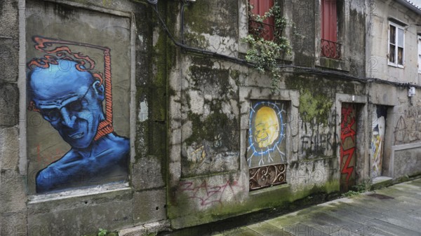 Graffiti on an old building wall with blue figure and other drawings, pilgrims on Caminho Portugues, Portugal, Spain