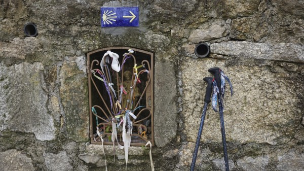 Window opening in a stone wall with pilgrim sticks, decoration, sign with scallop as a guide on the Caminho Portugues, pilgrims on the Caminho Portugues, Portugal