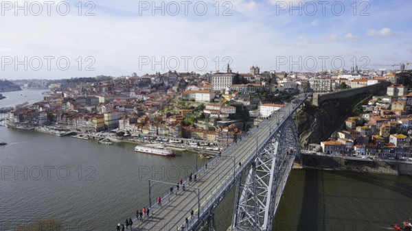 View from above of the metal bridge Ponte dom Luis across the Douro in Porto of a city with bridge and river under a blue sky and boats on the shore, Porto, Portugal