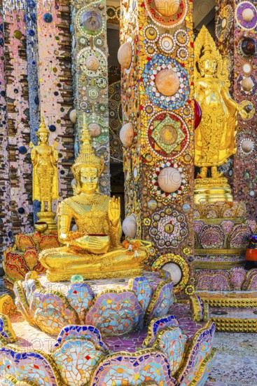 Gilded standing Buddha statues standing on pedestals decorated with mosaics and glass works of art, Buddhist temple complex Wat Phra That Sorn Kaew, Phetchabun province, Thailand