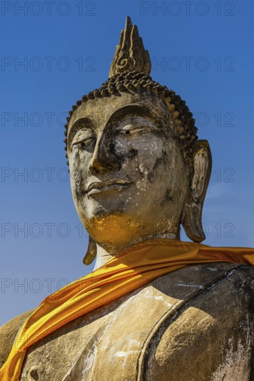 Stone Buddha statue decorated with yellow cloth, historic Buddhist temple complex, Ayutthaya, Thailand