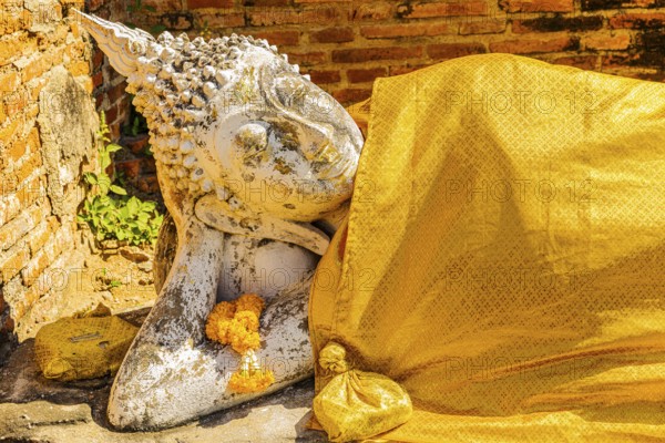 Reclining stone Buddha statue covered with yellow cloth, historic Buddhist temple complex, Ayutthaya, Thailand