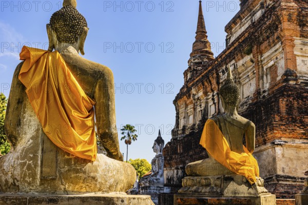 Stone Buddha statues decorated with yellow cloths, historic Buddhist temple complex, Ayutthaya, Thailand