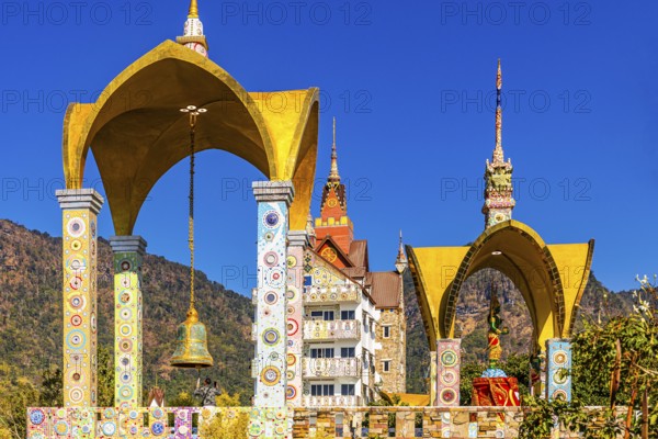 Round arch bell tower decorated with colorful mosaics and glass works of art, Buddhist temple complex Wat Phra That Sorn Kaew, Phetchabun province, Thailand