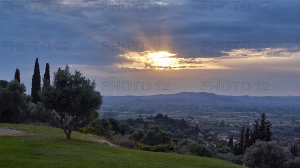 View of a quiet landscape with illuminated sky and vegetation at dusk, Hotel Europa, garden restaurant and view of the surrounding landscape, Olympia, Peloponnese, Greece