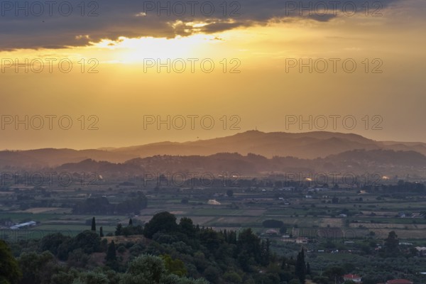 Fields and hills in the distance under a glowing sky at sunset, Hotel Europa, garden restaurant and view of the surrounding countryside, Olympia, Peloponnese, Greece