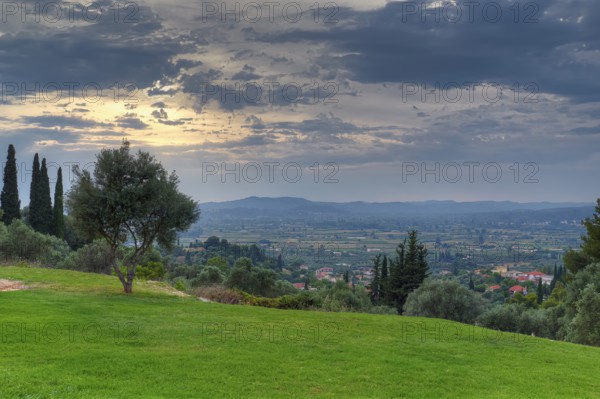 Wide landscape with a focus on a cloudy sky and isolated trees, Hotel Europa, garden restaurant and view of the surrounding landscape, Olympia, Peloponnese, Greece