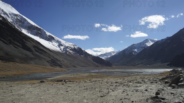 Snowy mountain peaks surround a wide and sparkling clear valley, trekking in Ladakh, Himalayas, India