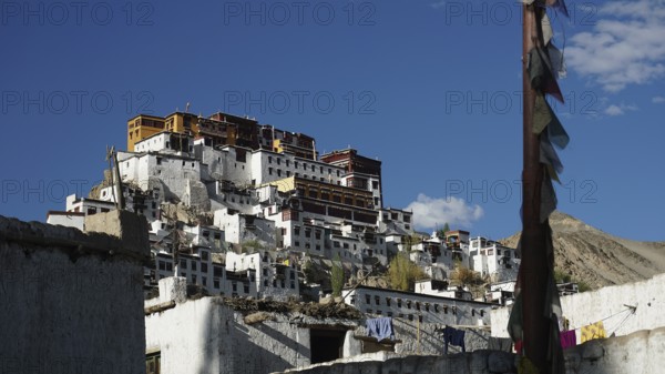Thiksey mountain monastery with white walls and prayer flags under a cloudless sky, Indus Valley, trekking in Ladakh, Himalayas, India