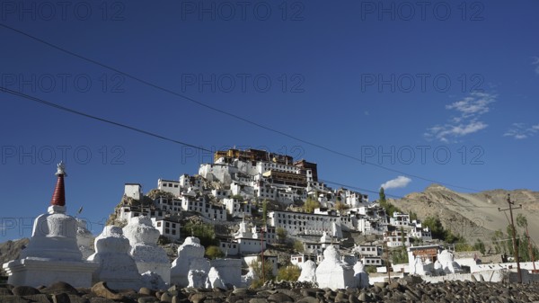 The sprawling Thiksey Buddhist monastery with several stupas against a mountain backdrop under a blue sky, trekking in Ladakh, Himalayas, India