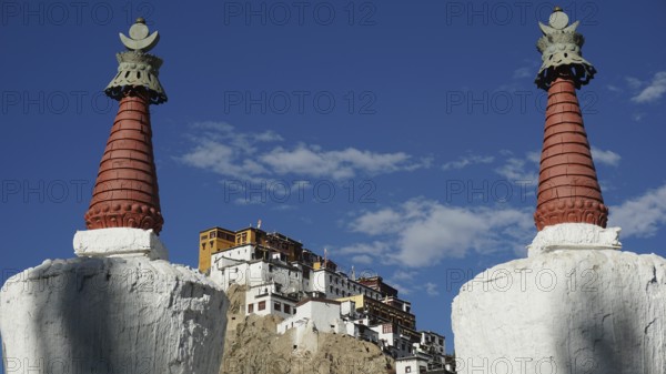 View through two stupas towards Thiksey monastery on a hill under blue sky, Indus Valley, trekking in Ladakh, Himalayas, India
