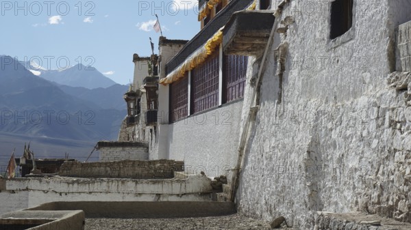 Old secluded Buddhist monastery with white walls against a backdrop of mountains, trekking in Ladakh, Himalayas, India